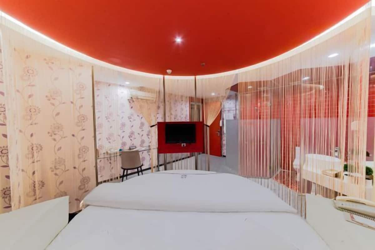 Un dormitorio moderno con techo curvo, televisor de pantalla plana, un escritorio pequeño y una cama.