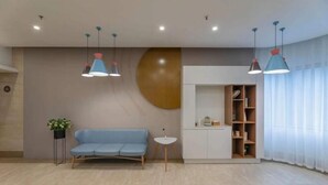 A modern room with a blue sofa, a small white table, and a white cabinet with shelves. - Homeinn Hotel (Ningbo Tianyi Square Center) (Ningbo)