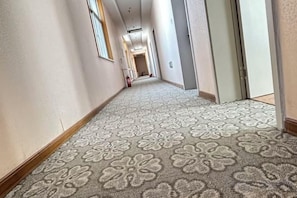 Ein mit Teppich ausgelegter Flur mit floralem Muster, der zu einer Tür führt.