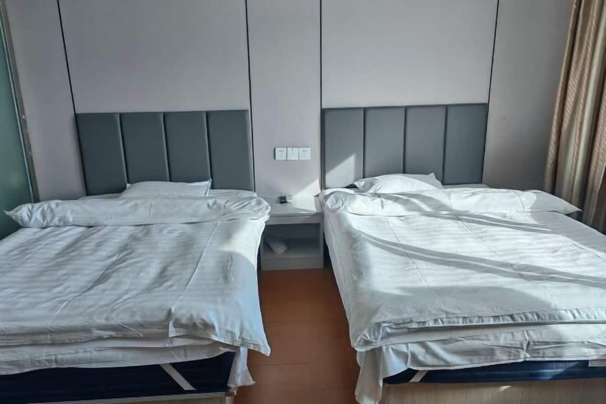 Dos camas individuales con cabeceras, una mesita de noche y un enchufe de pared.