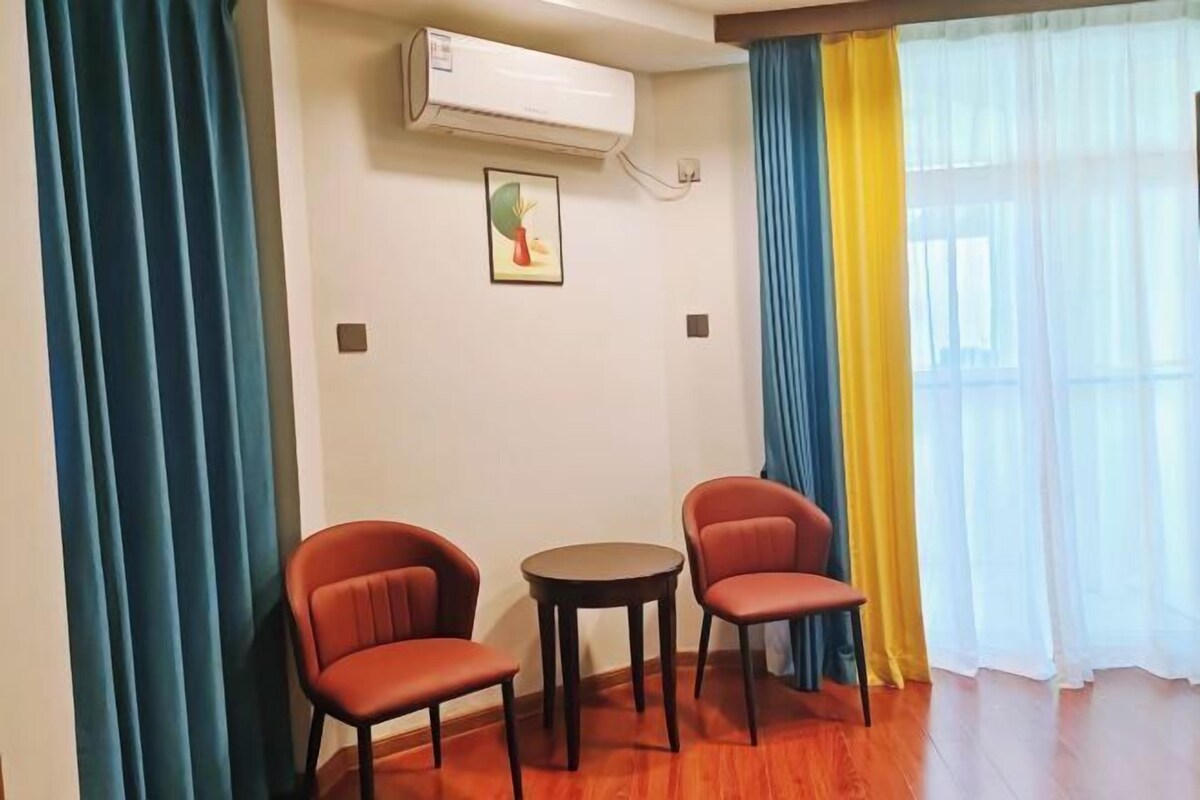 A room with two red chairs, a small round table, and a wall-mounted air conditioner.