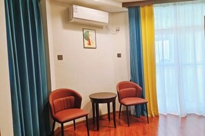 A room with two red chairs, a small round table, and a wall-mounted air conditioner. - Yaduo Holiday Hotel (Zhongshan)