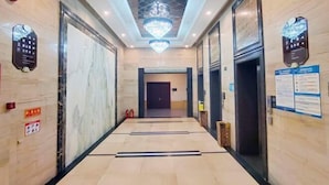 A hotel corridor with a chandelier, marble walls, and a door at the end. - Yaduo Holiday Hotel (Zhongshan)