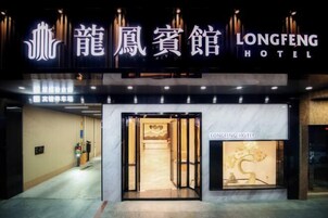 Exterior del Hotel Longfeng con fachada moderna, entrada destacada y recepción visible.