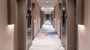 Un pasillo largo y estrecho con piso estampado, puertas a ambos lados e iluminación empotrada en el techo.