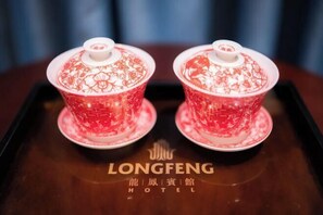 Two red teapots with floral designs on a tray with the Longfeng Hotel logo.