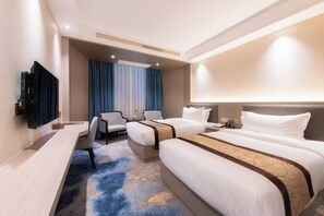 A hotel room with two beds, a desk, a chair, a TV, and a large window with curtains. - Longfeng Hotel (Enping)