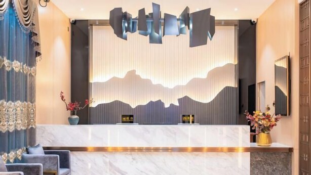 Zona de recepción de un hotel con mostrador de mármol, decoración moderna y asientos.