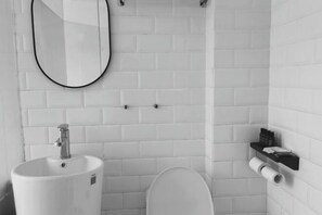 Un baño con lavamanos blanco, un espejo, un inodoro y un perchero para toallas.