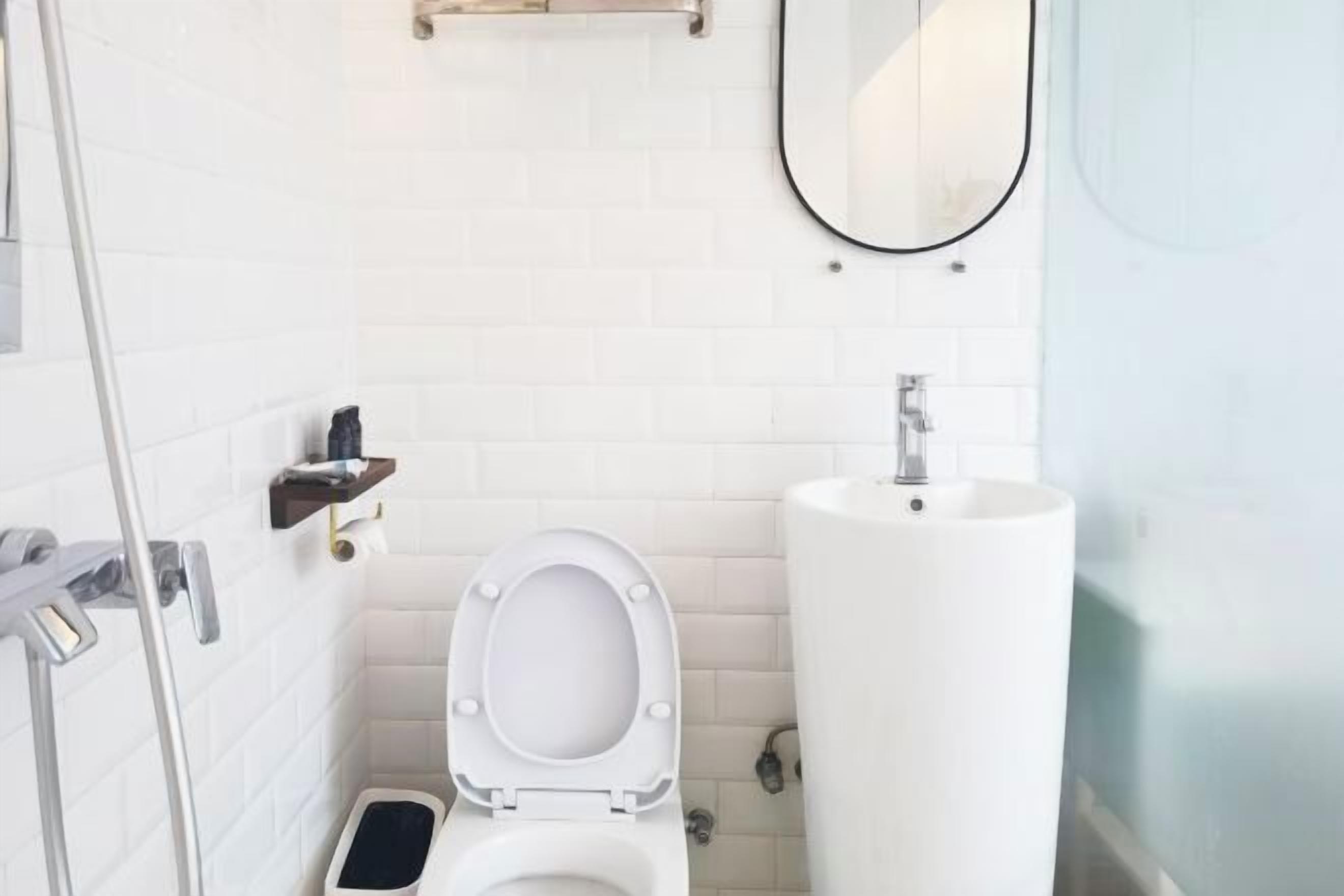 Une petite salle de bain moderne avec des toilettes blanches, un lavabo et un miroir.