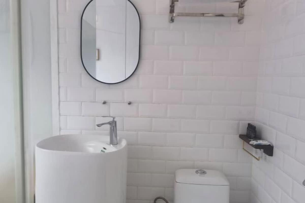Une salle de bain avec un lavabo blanc, des toilettes et un miroir au mur.