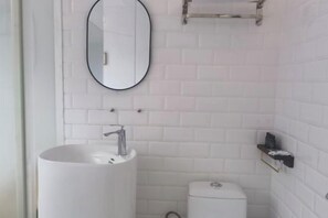 Une salle de bain avec un lavabo blanc, des toilettes et un miroir au mur.