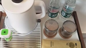 A white kettle, two bottles of water, two glasses with a brown substance, a green power strip, and a hotel brochure. - XUQIANFENG (Shenzhen)