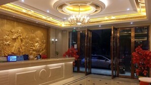 A hotel lobby with a reception desk, a chandelier, and a large window overlooking the street. - Haixing Business Hotel (Zhongshan)