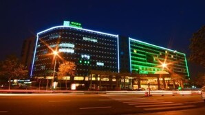 A hotel with multiple floors, a prominent sign at the top, and a well-lit facade. - Haixing Business Hotel (Zhongshan)
