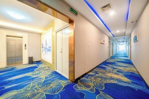 Un corridoio d'albergo con tappeto decorato, porte e un lungo androne.
