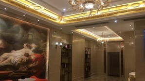 A lobby with a large classical painting, a chandelier, and a modern elevator. - Haixing Business Hotel (Zhongshan)