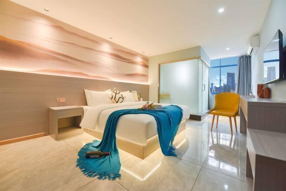 Een moderne hotelkamer met een groot bed, een bureau, een stoel en uitzicht op de stad.