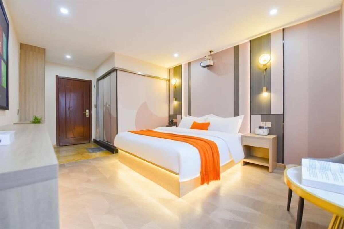 Een moderne hotelkamer met een groot bed, nachtkastjes, een bureau en een glazen scheiding.