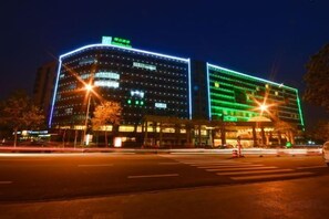 A multi-story hotel with a prominent signage, a well-lit facade, and a crosswalk in the foreground. - Haixing Business Hotel (Zhongshan)