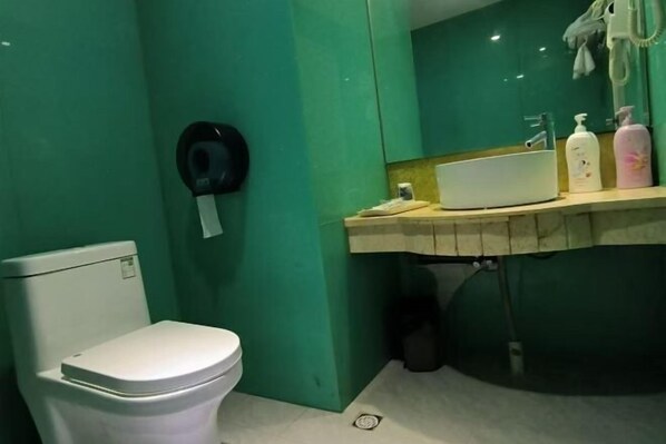 A bathroom with a toilet, a sink, and a mirror. - Haixing Business Hotel (Zhongshan)