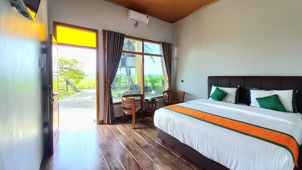 Une chambre d’hôtel avec un grand lit, un plancher en bois, une fenêtre avec des rideaux et un appareil de climatisation fixé au plafond.