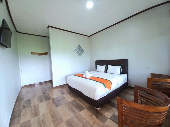 A hotel room with a bed, a wooden chair, and a small table.