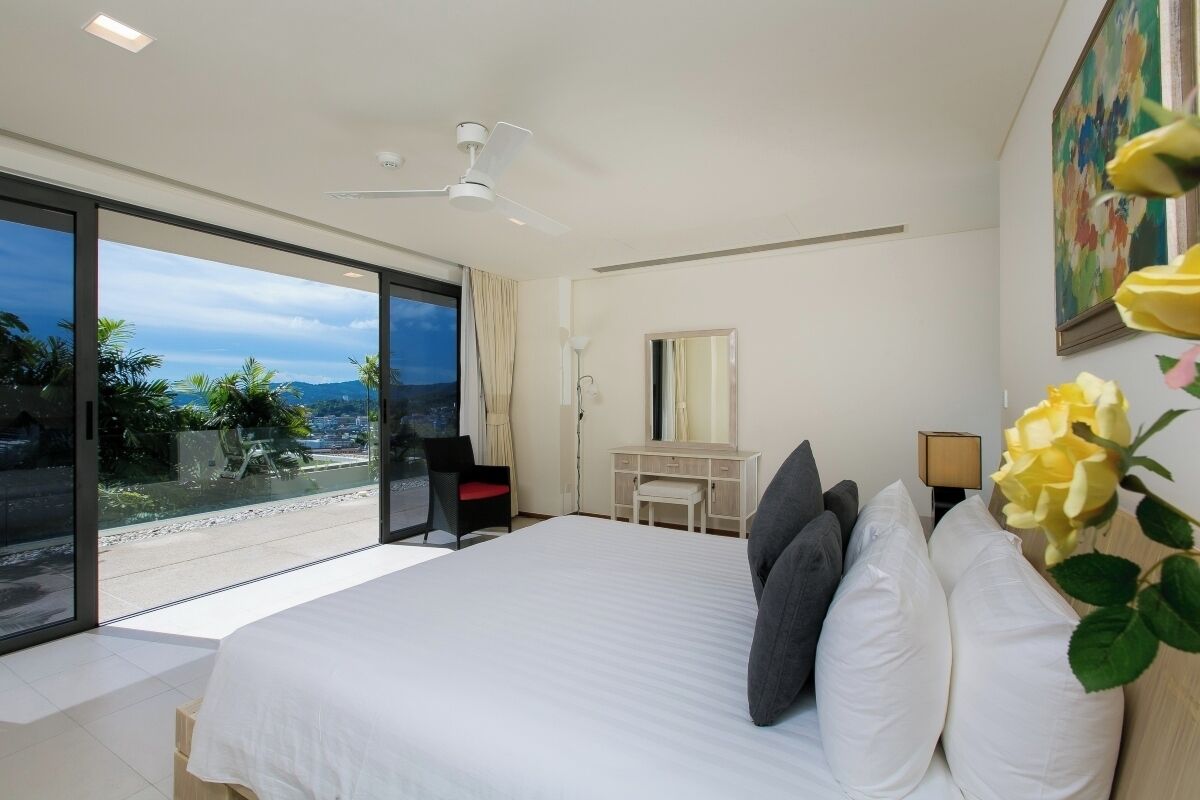 A modern hotel room with a large bed, a desk, and a view of the outdoors.
