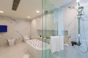 A modern bathroom with a glass-enclosed shower, a freestanding bathtub with rose petals, a toilet, and a sink. - The Heights Penthouse A5 3Bedrooms Seaview near Kata Beach (Muang)