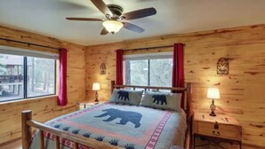 A wooden cabin bedroom with a bed, two nightstands, a ceiling fan, and windows with curtains. - Happy cabin in Heber (Heber)
