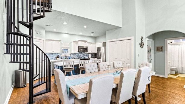 A spacious kitchen with white cabinets, a central island, and a dining area with a large table and chairs.