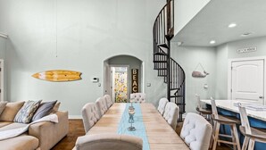A dining area with a long table, chairs, and a staircase.