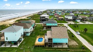 A coastal residential area with houses, a beach, and a clear sky.