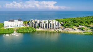 Un complexe résidentiel moderne composé de plusieurs bâtiments, situé au bord de l’eau et offrant une vue sur la mer.