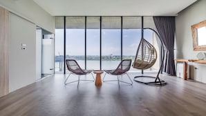 Une pièce spacieuse avec une grande fenêtre, deux chaises, une table ronde et un fauteuil suspendu.