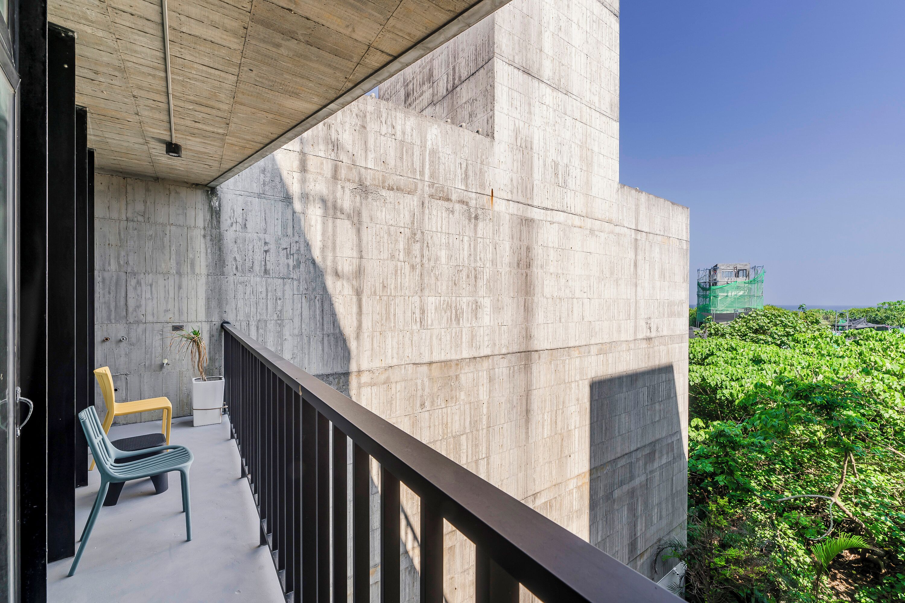 A balcony with a concrete wall, a wooden ceiling, and a view of a green landscape.