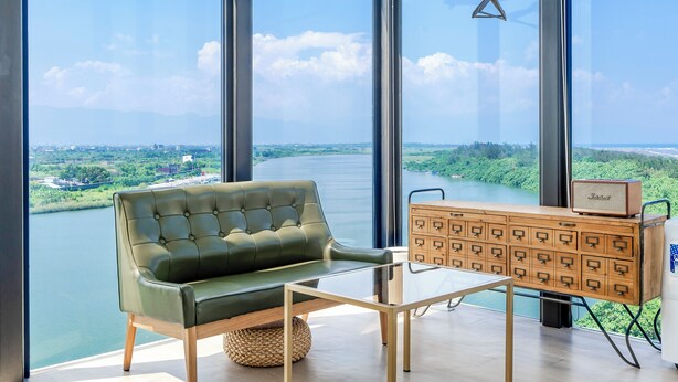 Un salón moderno con un sofá verde, una mesa de centro de vidrio y un mueble de madera con cajones.