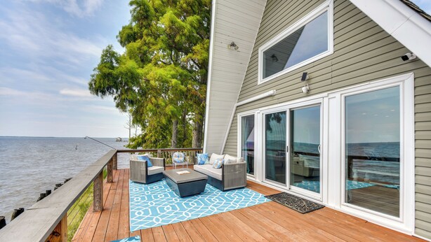 A deck with outdoor furniture, a view of the ocean, and a large sliding glass door. - Cabin on Albemarle Sound w/ Dock & 2 Kayaks (Shiloh)
