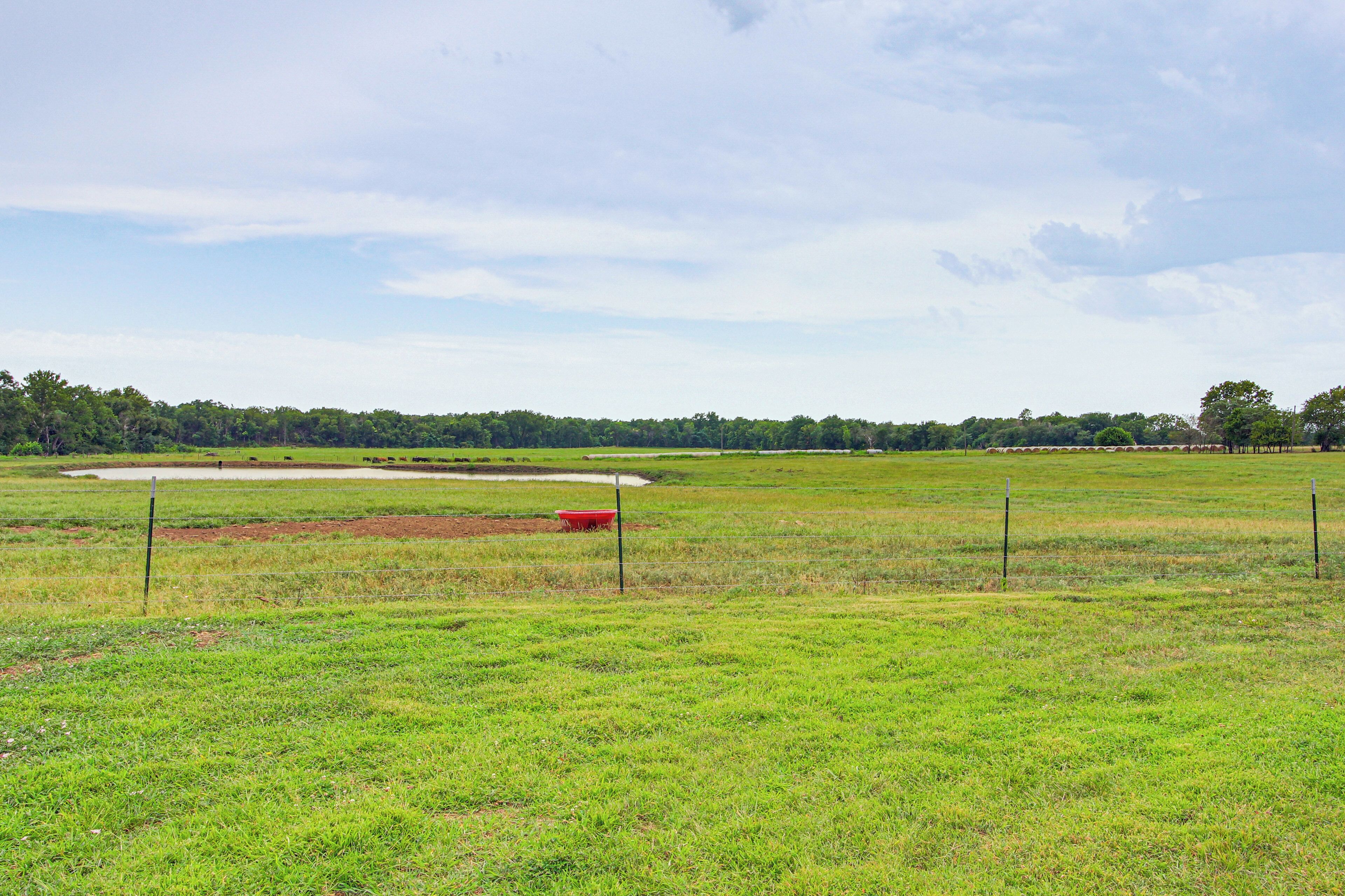 A large, open grassy field with a dirt track and a red object in the distance.