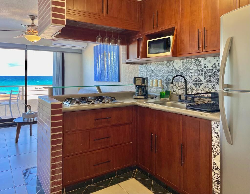A kitchen with wooden cabinets, a microwave, a refrigerator, a gas stove, and a coffee maker.