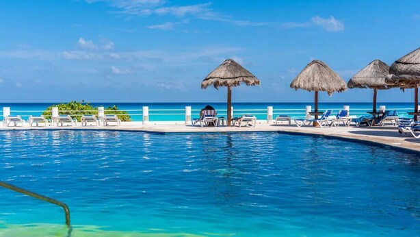 Une piscine à l’eau d’un bleu cristallin, des chaises longues et des parasols en chaume.
