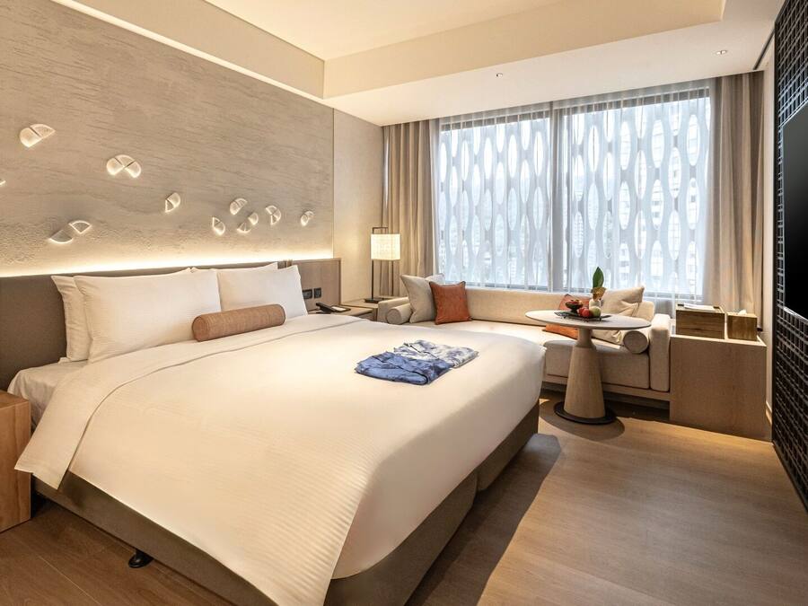 A modern hotel room with a large bed, a desk, and a TV.