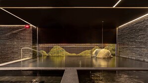 A modern indoor pool with a stone wall and a digital clock. - Wellspring by Silks Beitou (Taipei)