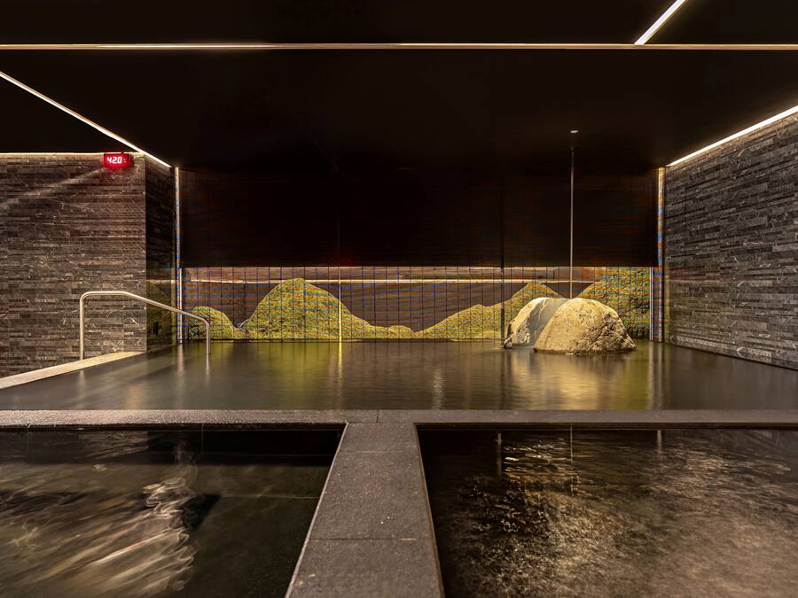 A modern indoor pool with a stone wall and a digital clock.