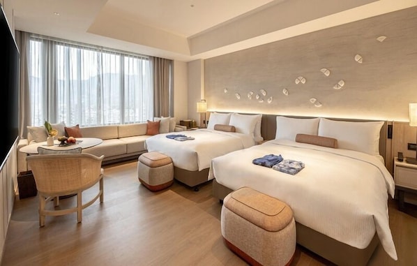 A modern hotel room with two beds, a sofa, a dining table, and a view of the city. - Wellspring by Silks Beitou (Taipei)