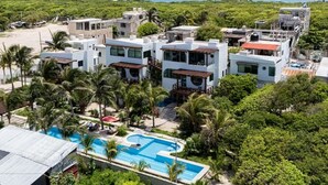 Un resort con varias edificaciones blancas, una piscina y vistas al océano.