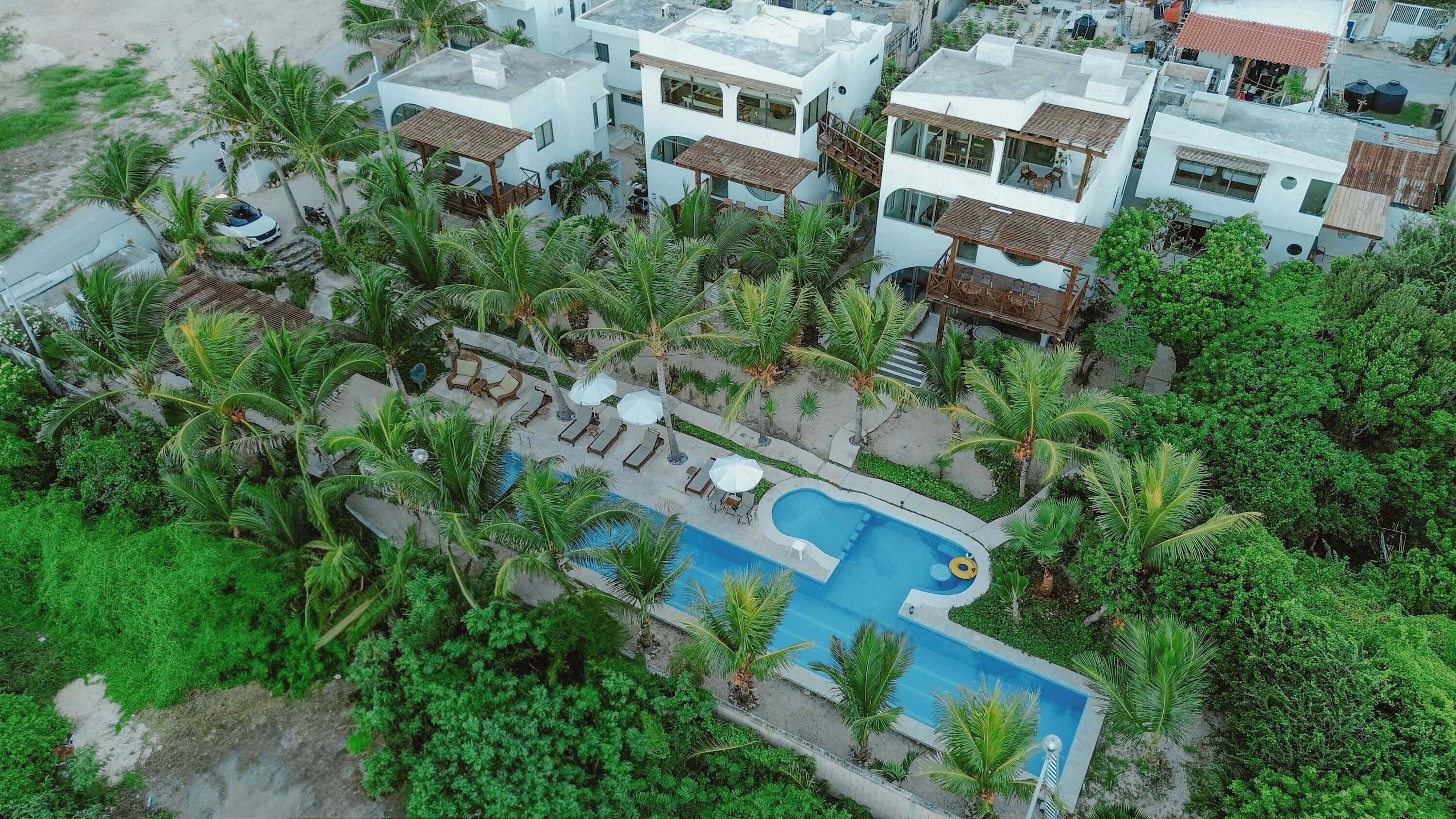 A residential area with modern houses, a swimming pool, and lush greenery.