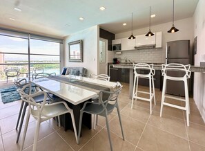 Enjoy meals at the large dining table surrounded by comfortable chairs, with a view of the pool and cityscape through large windows.