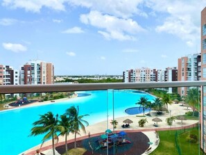 Relax by the expansive pool surrounded by palm trees and a children's play area with slides.