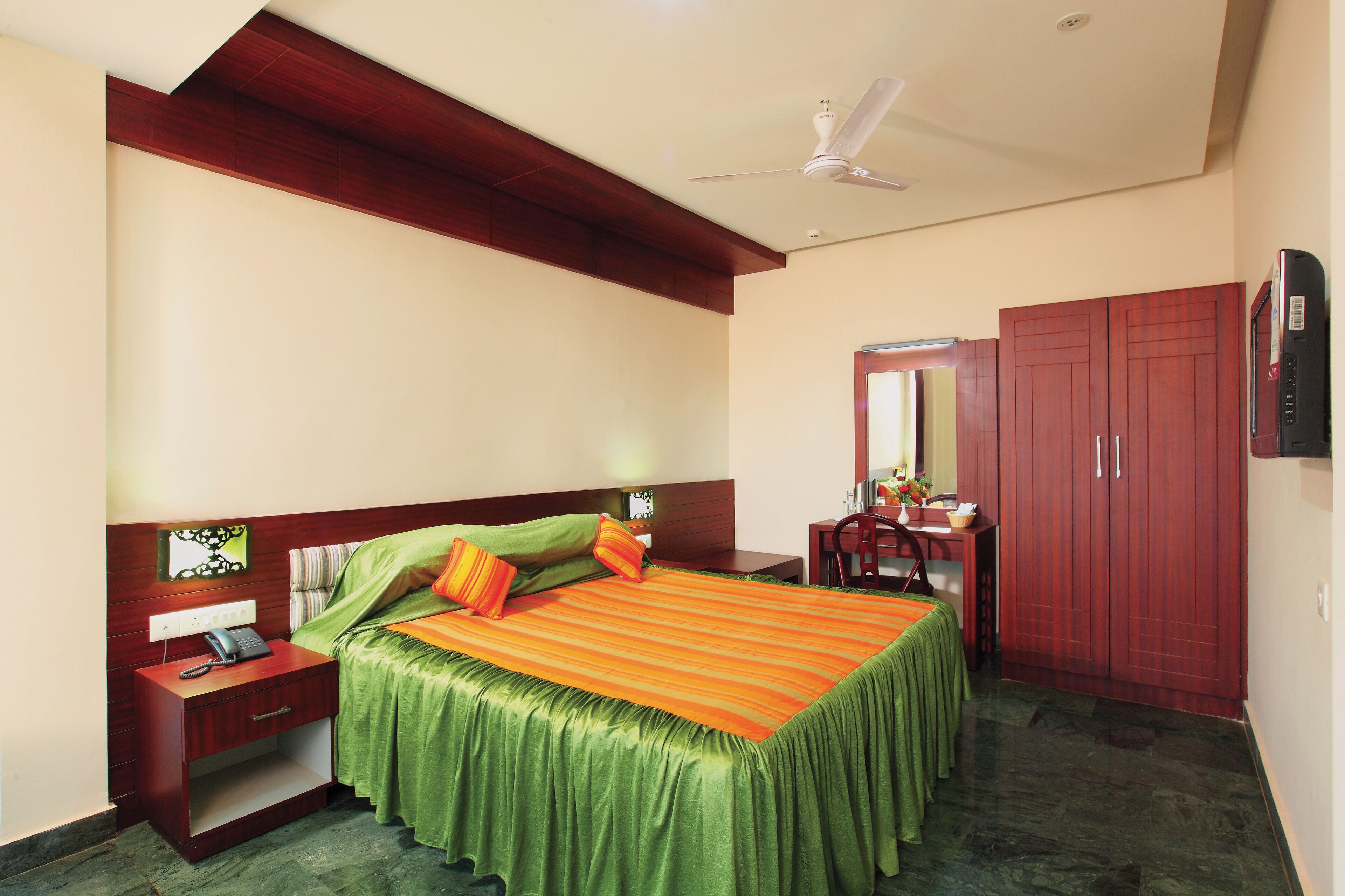 A bedroom with a bed, nightstand, desk, wardrobe, and a ceiling fan.